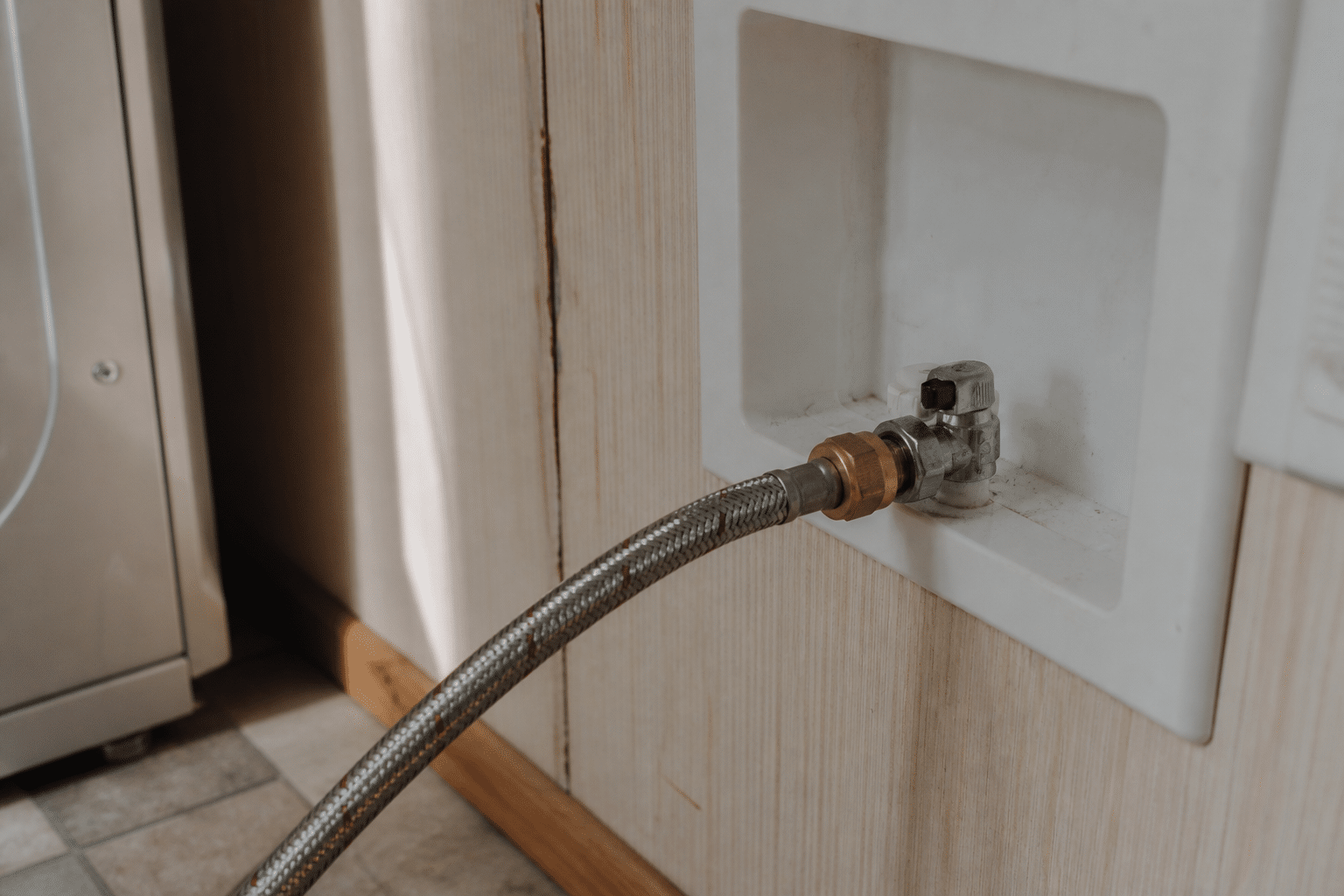Braided stainless steel washing machine supply hose in a mobile home laundry area