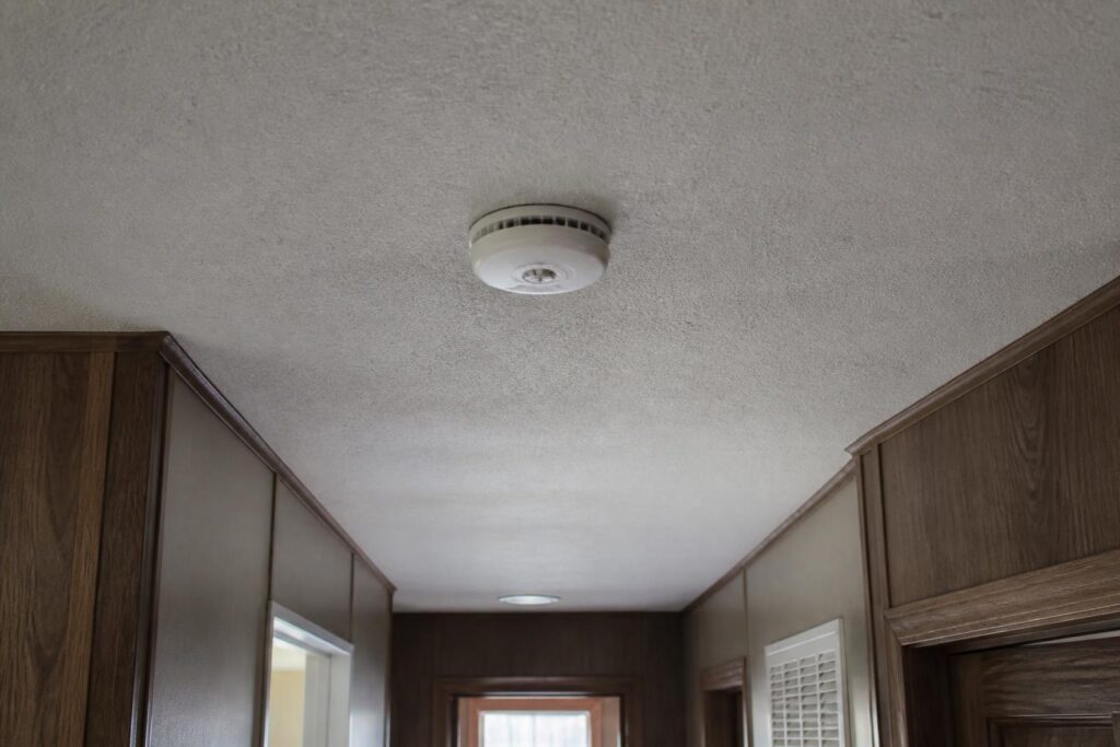 Smoke detector mounted on a hallway ceiling inside a manufactured home