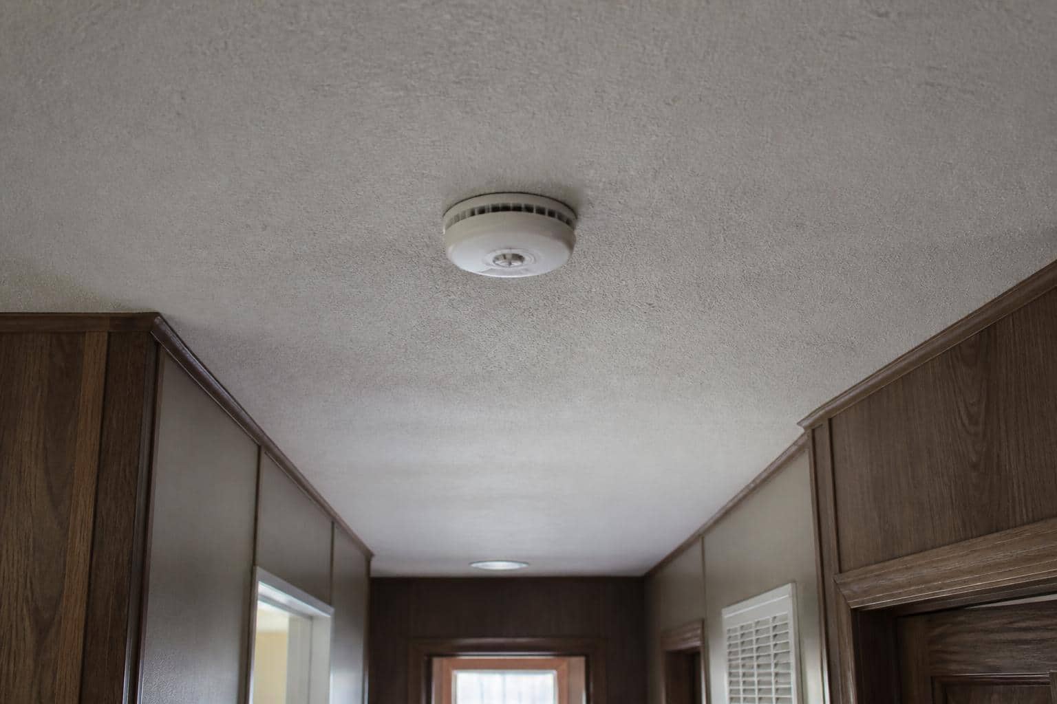 Smoke detector mounted on a hallway ceiling inside a manufactured home