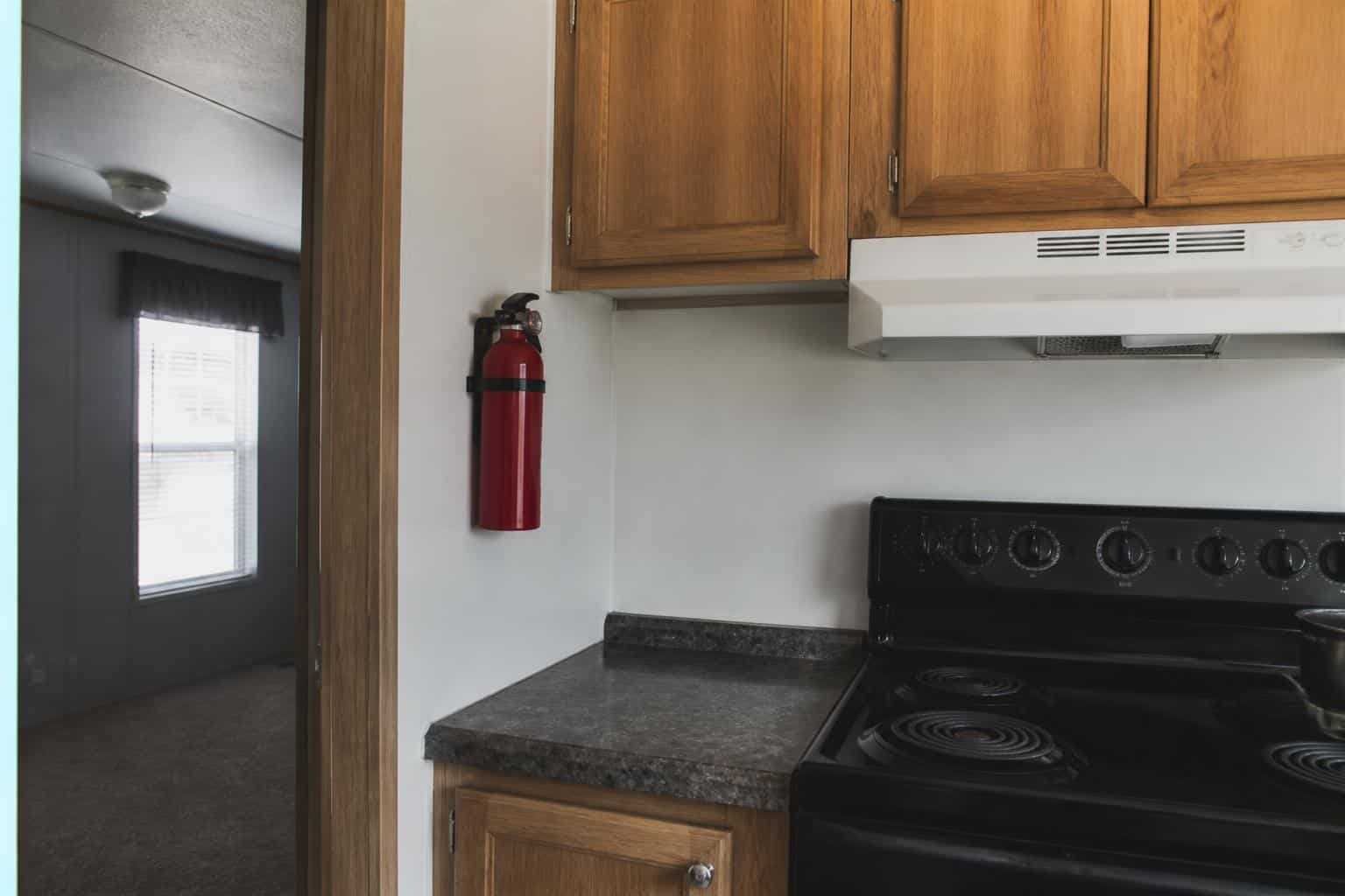 Portable fire extinguisher mounted on a kitchen wall near a stove