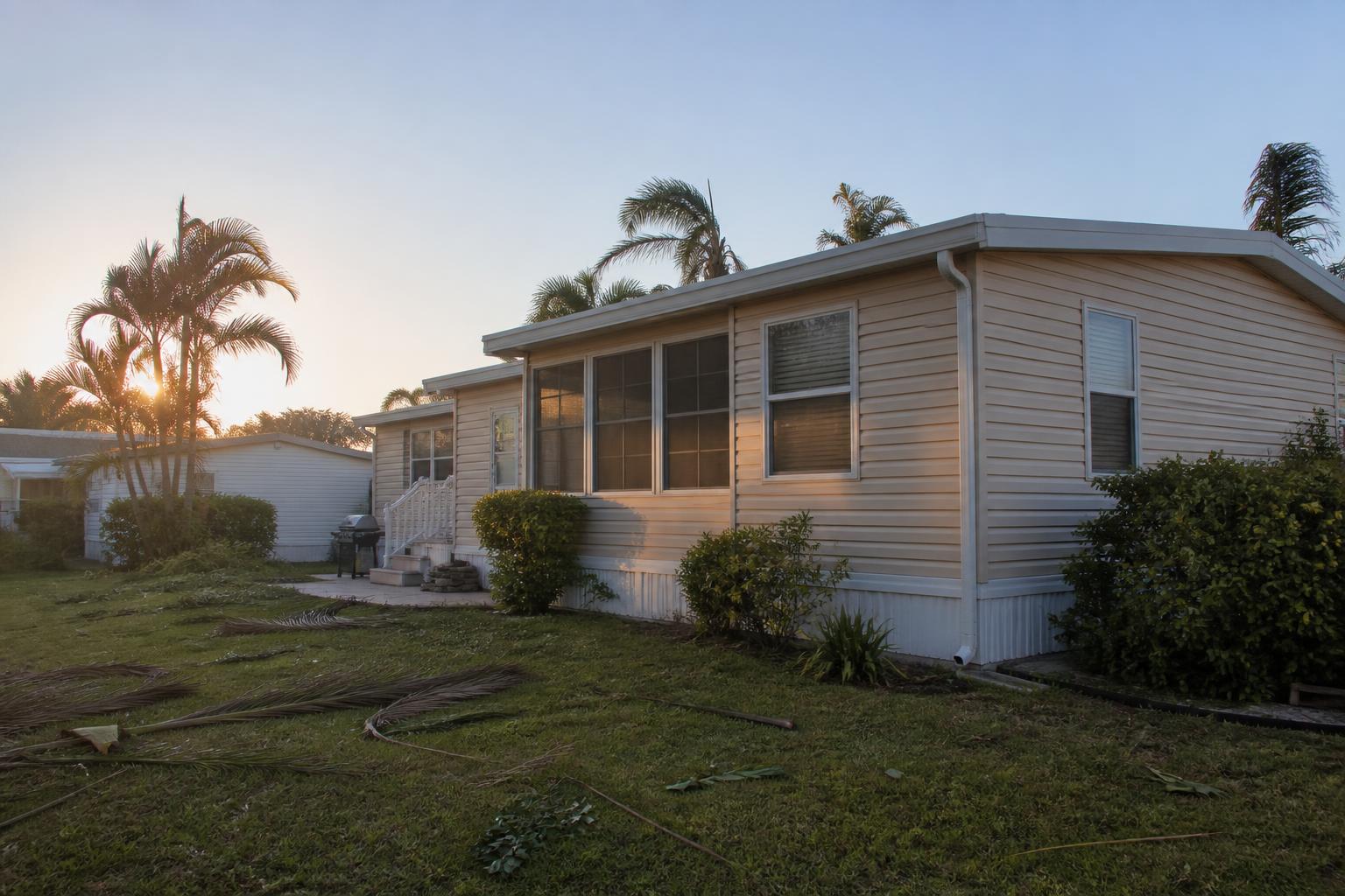 Manufactured home in a Florida community with a few fallen palm fronds on the lawn after a storm